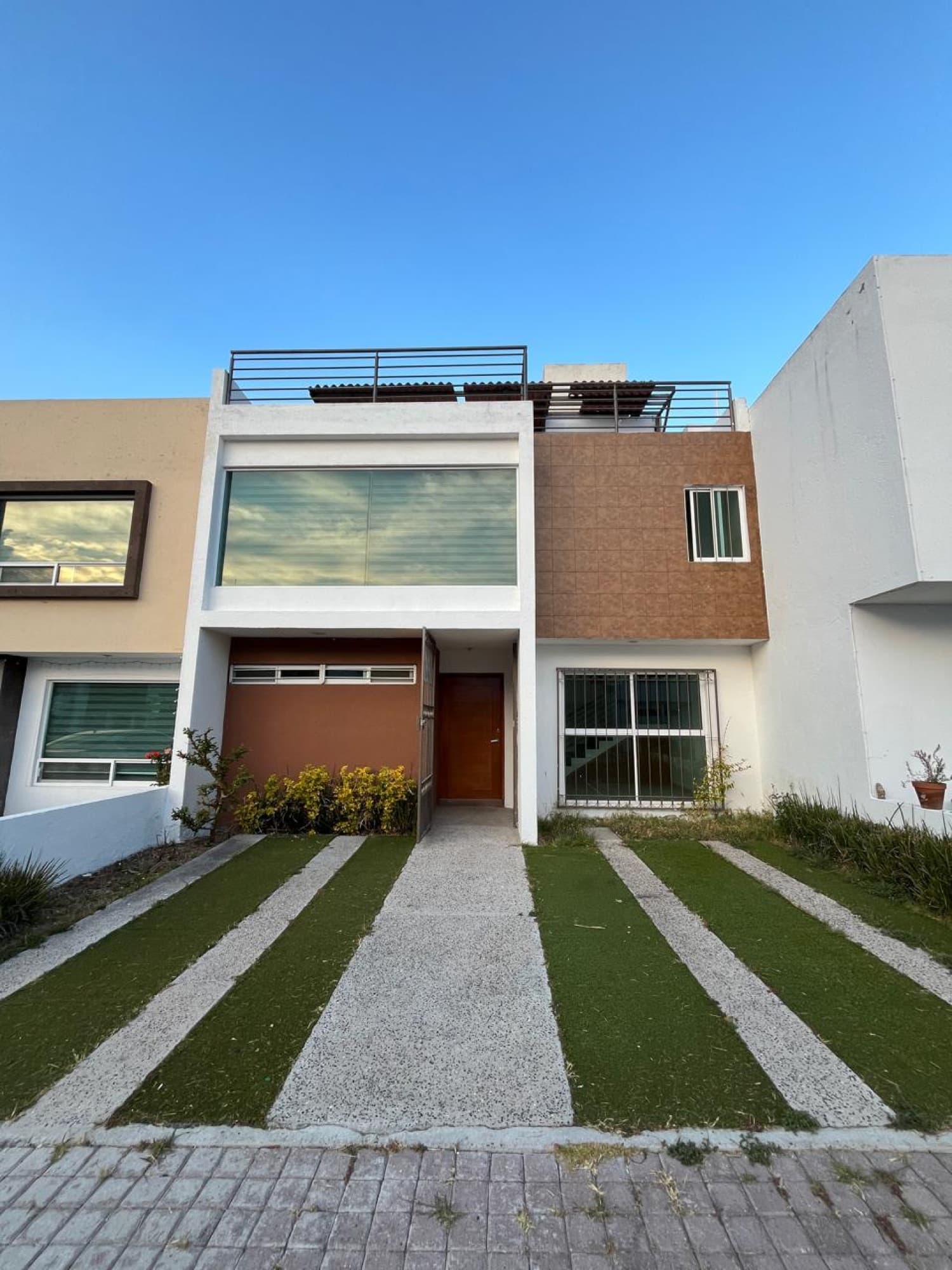Fachada de la casa al atardecer con jardín de acceso